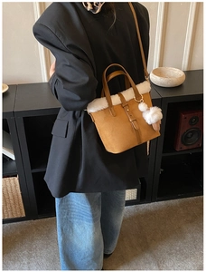 Brown suede bucket bag with white faux fur trim and pompom detail on female model