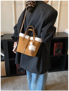 Detail of vintage brown suede bucket bag with white faux fur trim and plush charms