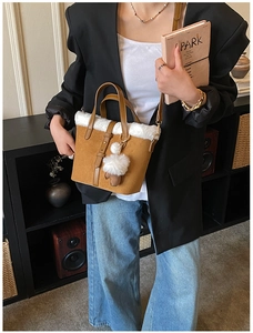 Detail of a brown fuzzy bucket bag with white faux fur trim and cute bear charm accent