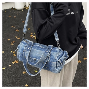 Dettaglio della borsa baguette in denim blu retrò con borchie argentate e tracolla regolabile