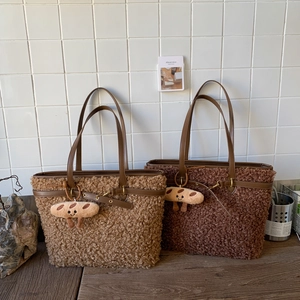 Detail of plush teddy fur tote bags with leather handles and cute bread pendants