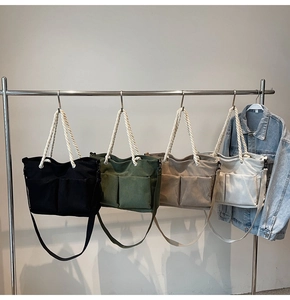 Detail of four colorful corduroy tote bags with rope handles hanging on a metal rack