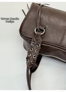 Detailed view of woven leather strap with metallic eyelets on dark brown shoulder bag