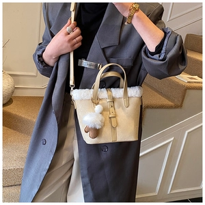 Detail of beige faux suede bucket bag featuring white plush trim and mushroom charm detail