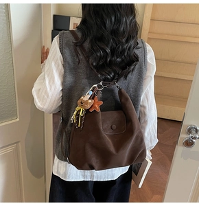 Detail of a large brown nylon tote bag featuring a cute bear and star plush charm