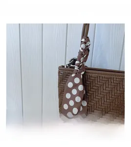 Detailed close-up of brown woven shoulder bag with stylish polka dot scarf accessory