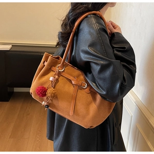 Detail of caramel suede tote bag with plush charms and thin shoulder straps