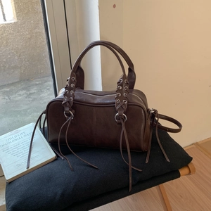 Détail du sac Boston en cuir marron avec anneaux argentés et finitions de laçage croisé
