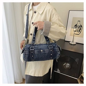 Dettaglio borsa a cilindro in denim blu scuro con rivetti argentati e tracolla regolabile