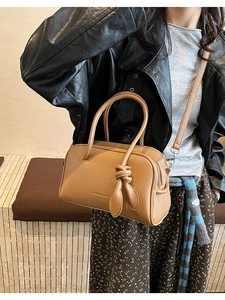 Nahaufnahme der braunen Tasche mit Litschi-Muster, geprägtem Text und Knotendetail