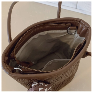 Detailed view of brown woven handbag interior with zipper pocket and floral scarf