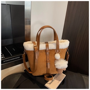 Close-up of caramel faux suede bucket bag with white plush trim and fuzzy pompom charm