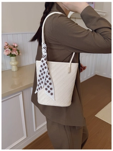 Détail du sac seau tressé crème avec texture en point de croix et foulard à pois élégant