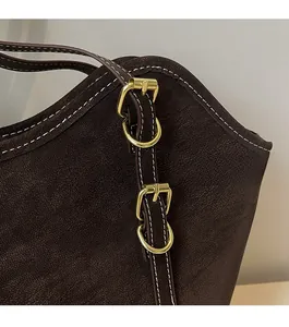 Detail of dark brown leather tote with premium gold-tone hardware and contrast stitching
