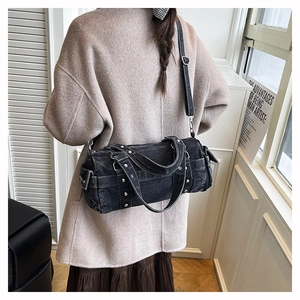 Vista posteriore modella con borsa a cilindro in denim nero con dettagli in borchie