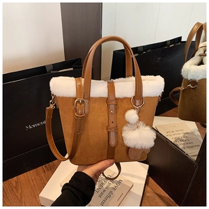 Detail of vintage brown suede bucket bag featuring plush white faux fur trim and buckle