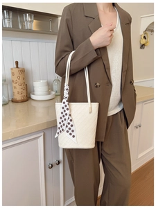Détail du sac seau tissé crème avec foulard à pois marron et fine bandoulière