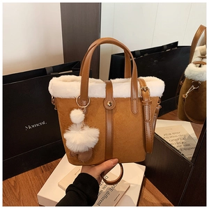Detail of brown suede bucket bag with white faux fur trim and gold hardware accents