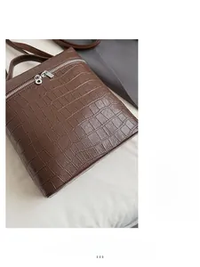 Detail of brown crocodile pattern handbag featuring a sleek silver double zipper closure