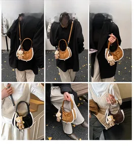 Détail du sac croissant à bordure peluche avec texture suède et pendentif ours