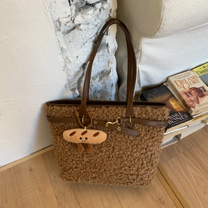 Close-up of brown plush tote bag with leather straps and a cute baguette charm