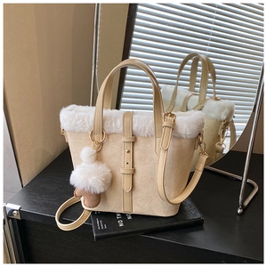 Detail of beige suede bucket bag with white faux fur trim and gold metal hardware