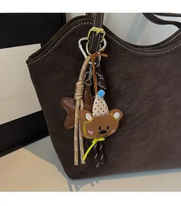Detail of cute plush bear bag charm with polka dot hat and star leather accessory