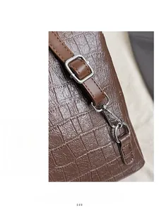 Detailed close-up of silver square buckle and hook on croco-embossed brown leather bag