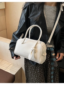 Details der weißen Boston Bag aus Leder mit Narbenstruktur und markantem Knotengriff Design