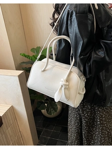 Detail der weißen Handtasche mit Litschi-Muster, Knotendekor und Schultergurt