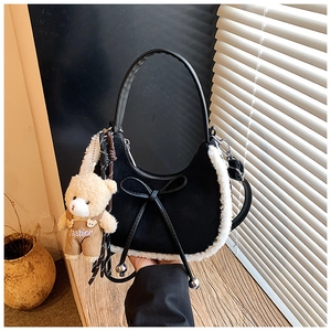 Détail du sac à main noir en daim avec bordure pelucheuse et breloque ours en peluche