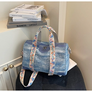 Detail of light blue denim Boston bag with floral embroidery and SIJICHAO logo