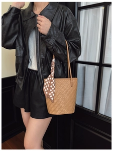 Detail of woven bucket bag with polka dot scarf accessory styled on a leather jacket