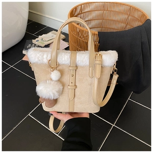 Detail of beige plush bucket bag with metal handles, white faux fur trim, and a fluffy charm