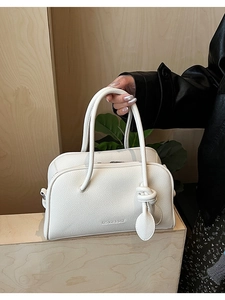 Dettaglio borsa a tracolla bianca in pelle martellata con ciondolo a nodo e logo