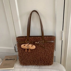 Close-up of a brown fluffy tote bag with leather handles and a bread plush keychain