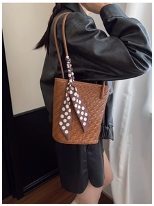 Détail du sac seau marron tressé avec foulard en soie à pois et bandoulière en cuir