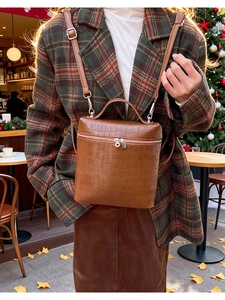 Brown crocodile pattern faux leather handbag with adjustable strap in outdoor setting