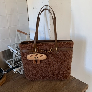 Detail of dark brown plush tote bag with sherpa texture and cartoon baguette charm