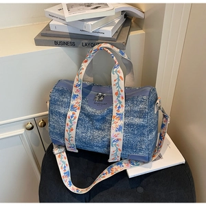 Detail of blue denim barrel bag with colorful floral embroidered detachable shoulder strap