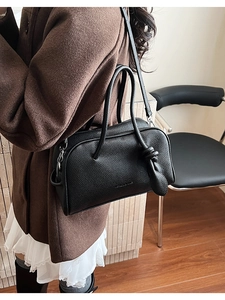 Dettaglio borsa quadrata in pelle martellata nera con manico decorativo a nodo chic