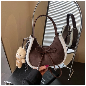 Détail d'un sac à main en daim marron avec bordure en fausse fourrure et breloque ours