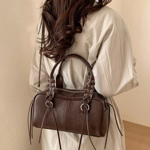 Détail du sac Boston en cuir marron foncé avec lacets croisés et glands latéraux