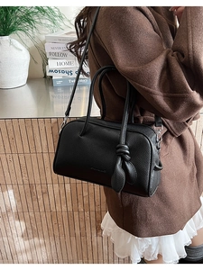 Elegante borsa Boston in pelle nera martellata abbinata a un cappotto marrone e pizzo