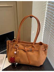 Minimalist caramel brown suede tote bag with metal hardware and decorative tassel detail