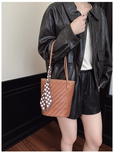 Detail of a large woven brown tote bag with a polka dot scarf accessory on handle