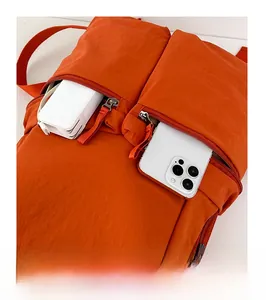 Front pocket close-up of bright orange nylon backpack showing phone and power bank storage