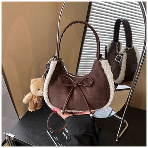 Détails du sac à main en daim marron avec bordure en peau lainée et breloque ours