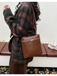 Brown crocodile embossed handbag held by model in a vintage autumn fashion setting