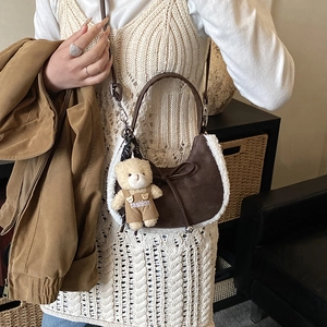 Gros plan sur un sac croissant marron avec bordure en fausse fourrure et breloque
